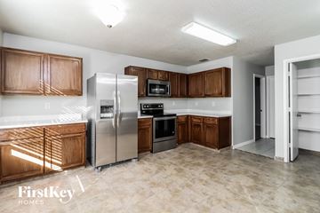 Fort Worth house for rent - A kitchen with wooden cabinets and a refrigerator.