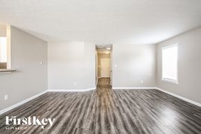 Indianapolis house for rent - A spacious room with wooden flooring and a door in the middle.