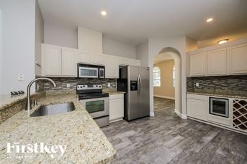 Orlando house for rent - a kitchen with stainless steel appliances and white cabinets