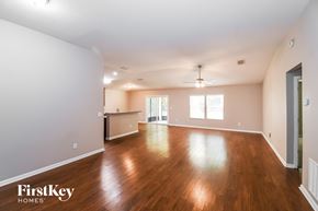 Jacksonville house for rent - A spacious room with wooden floors and a ceiling fan.