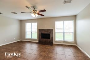Conroe house for rent - a living room with a fireplace and a ceiling fan