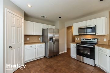Conroe house for rent - a kitchen with white cabinets and stainless steel appliances