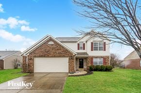 Indianapolis house for rent - a brick house with a white garage door and a green lawn