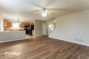 Indianapolis house for rent - an empty living room and kitchen with wood flooring and a ceiling fan