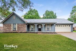 Bartlett house for rent - a blue house with a green lawn and a white garage