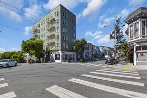 San Francisco apartment for rent - A street view with a white car and a tall building.