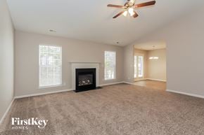 Charlotte house for rent - an empty living room with a fireplace and a ceiling fan