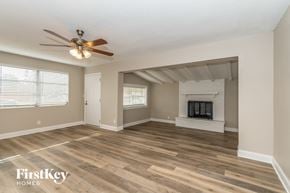 Jacksonville house for rent - A spacious living room with a fireplace and a ceiling fan.