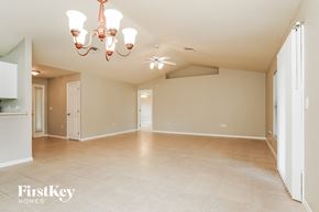 Lehigh Acres house for rent - A large empty room with a chandelier and a ceiling fan.