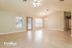 Lehigh Acres house for rent - A spacious room with a fan and a chandelier.