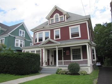 Syracuse apartment for rent - a red and white house with a porch and a green house next to it
