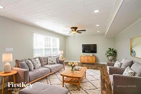 Bargersville house for rent - A living room with a grey couch, a wooden coffee table, a flat screen TV, and a ceiling fan.