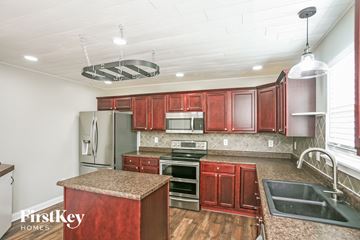 Bargersville house for rent - A kitchen with red cabinets and a granite island.