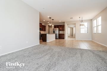 Buckeye house for rent - A spacious living room with a grey carpet and a kitchen in the background.