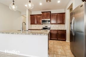 Buckeye house for rent - A kitchen with a white counter top and brown cabinets.