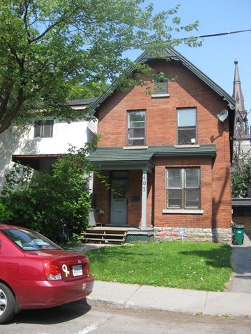 Ottawa apartment for rent - A red car is parked in front of a brick house.