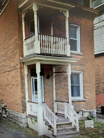 Ottawa apartment for rent - A two-story brick house with a balcony and stairs leading to the front door.