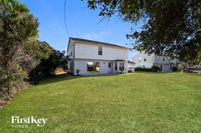 North Port house for rent - a white house sitting on top of a grass covered hill