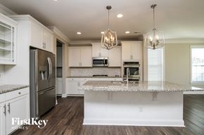 Mooresville house for rent - a kitchen with white cabinets and a marble counter top