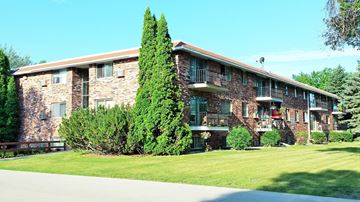 Fargo apartment for rent - a large brick apartment building with a green lawn and trees