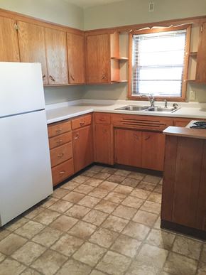 Fargo apartment for rent - an empty kitchen with wooden cabinets and a white refrigerator