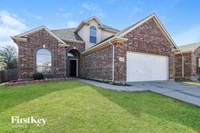 Fort Worth house for rent - a brick house with a white garage door and a lawn