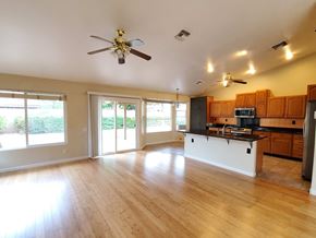 Chandler house for rent - an open kitchen and living room with wood floors and a ceiling fan