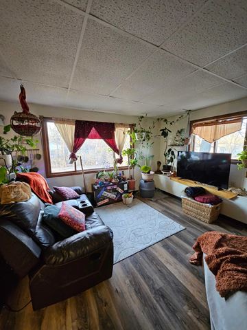 Wausau apartment for rent - A living room with a black leather couch and a wooden floor.