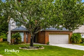 Fleming Island house for rent - a white garage door in front of a brick house with a tree