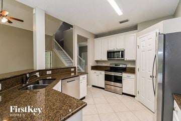 Fleming Island house for rent - a kitchen with white cabinets and granite counter tops and stainless steel appliances