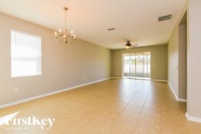 Haines City house for rent - A spacious room with a chandelier, ceiling fan, and sliding glass doors.