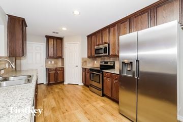 Denton house for rent - A kitchen with a stainless steel refrigerator and wooden cabinets.