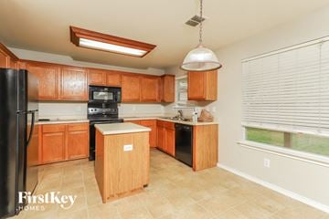 Converse house for rent - a large kitchen with wooden cabinets and black appliances
