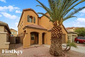 Phoenix house for rent - A palm tree stands in front of a tan house with a red car parked in the driveway.
