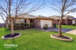 Arlington house for rent - A house with a brown roof and a garage door is surrounded by a well-manicured lawn and two trees.