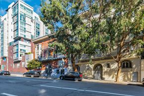 San Francisco apartment for rent - A tree in front of a building with a car parked on the side of the road.