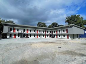 Houston apartment for rent - A grey building with red and white doors.