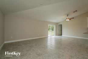 Lehigh Acres house for rent - an empty living room with a ceiling fan and tile floor