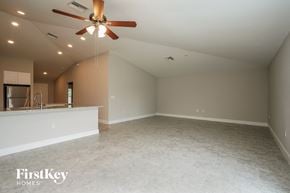 Lehigh Acres house for rent - a empty living room with a ceiling fan and a kitchen