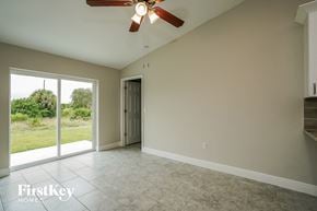 Lehigh Acres house for rent - an empty living room with a ceiling fan and a sliding glass door