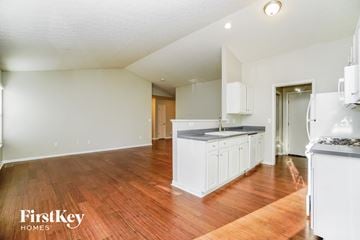 Reynoldsburg house for rent - a kitchen with white cabinets and a hardwood floor and a large white kitchen island