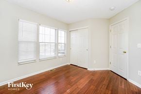 Reynoldsburg house for rent - a bedroom with wood floors and white walls and three windows