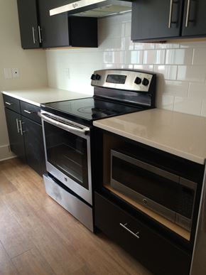St. Louis apartment for rent - A black stove top oven with a silver handle and a black microwave above it.