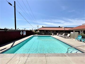 Bermuda Dunes apartment for rent - the pool is next to a building with chairs and a roof