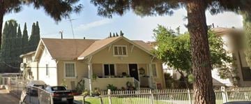 Whittier apartment for rent - A yellow house with a black car parked in front.