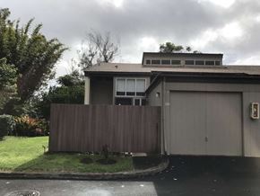 Mililani apartment for rent - A house with a grey garage door and a brown fence.