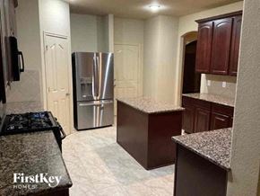 Fort Worth house for rent - A kitchen with a granite countertop and a stainless steel refrigerator.