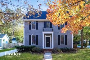 Greensboro house for rent - A house with a blue roof and a white door is surrounded by trees with yellow leaves.