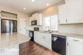 Colorado Springs house for rent - a kitchen with white cabinets and a counter top and a sink