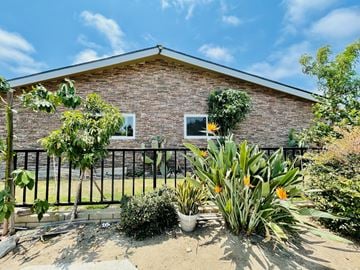 Huntington Beach apartment for rent - A house with a black fence and plants in front.